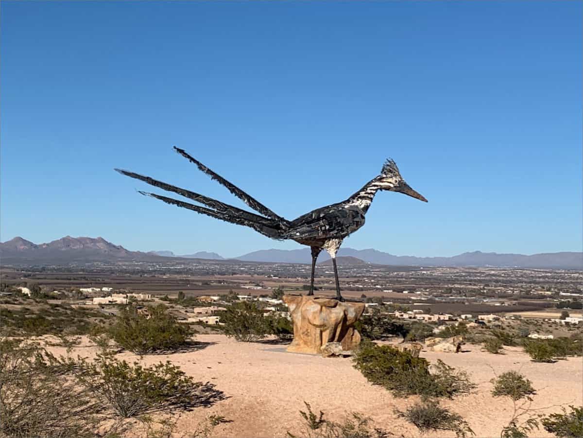 A unique landmark, a roadrunner statue on top of a hill in the desert.